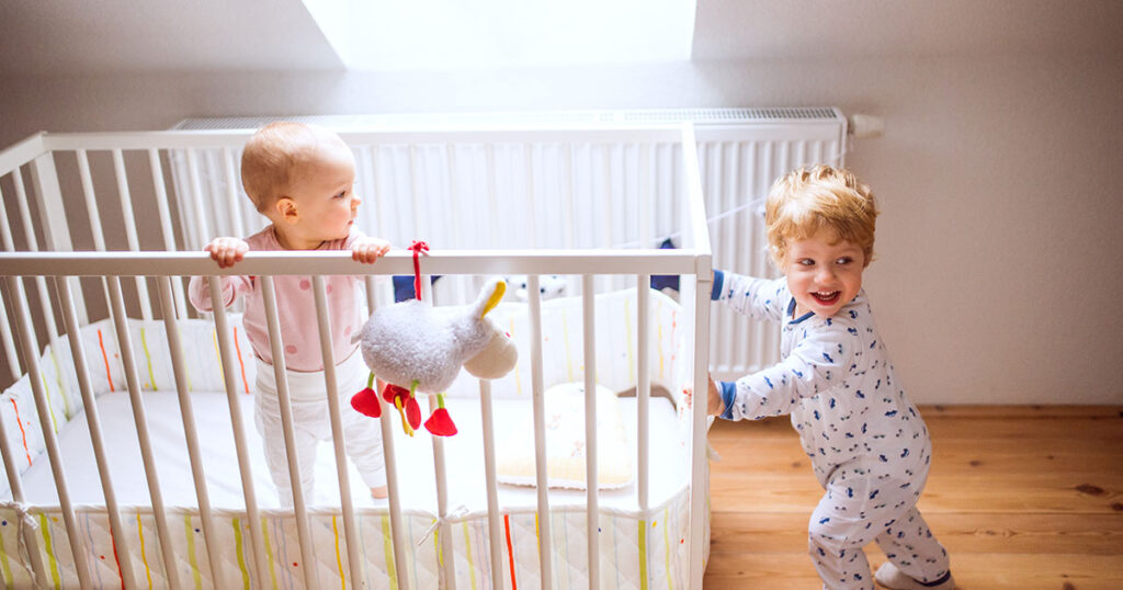 deux enfants jouant près d'un lit de bébé