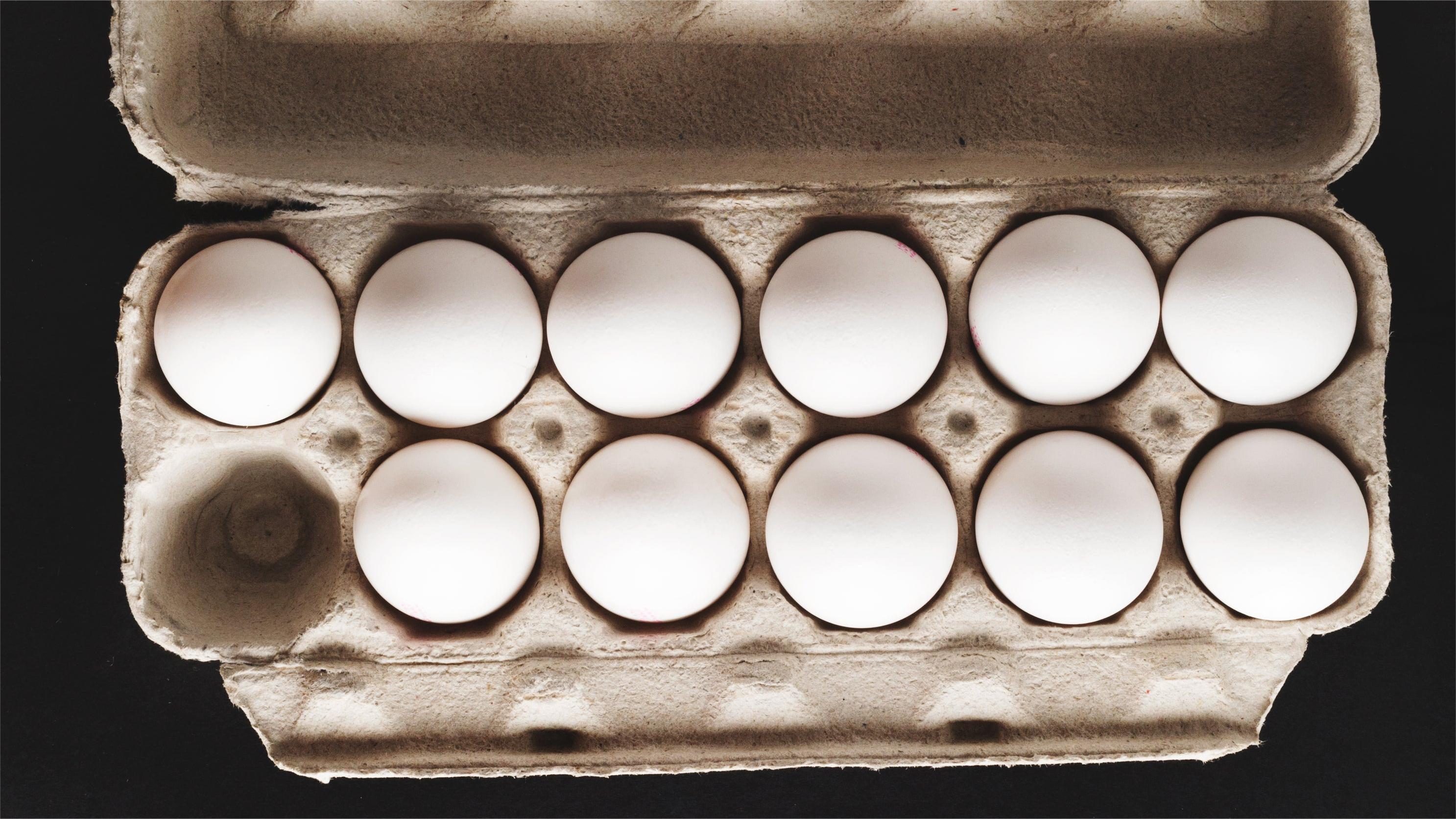 Eleven Eggs In Cardboard Carton On Black Background