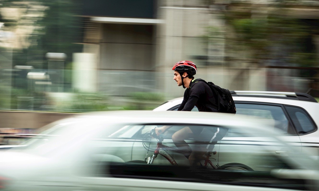 Man cycling through traffic 