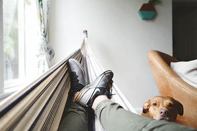 Man resting in a hammock and wearing shoes in the house