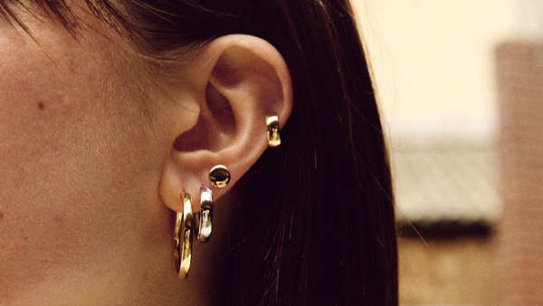 set of stacked gold earrings on a model
