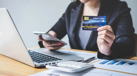 Utilize credit to build a beautiful life and gain financial freedom. Capital One Credit Card helps you build your financial foundation, and offers cashback, low-interest, travel rewards, and balance transfers all with NO annual fee, and top-notch fraud protection. Sign up today and keep building your success! woman holding credit card while sitting at her desk working