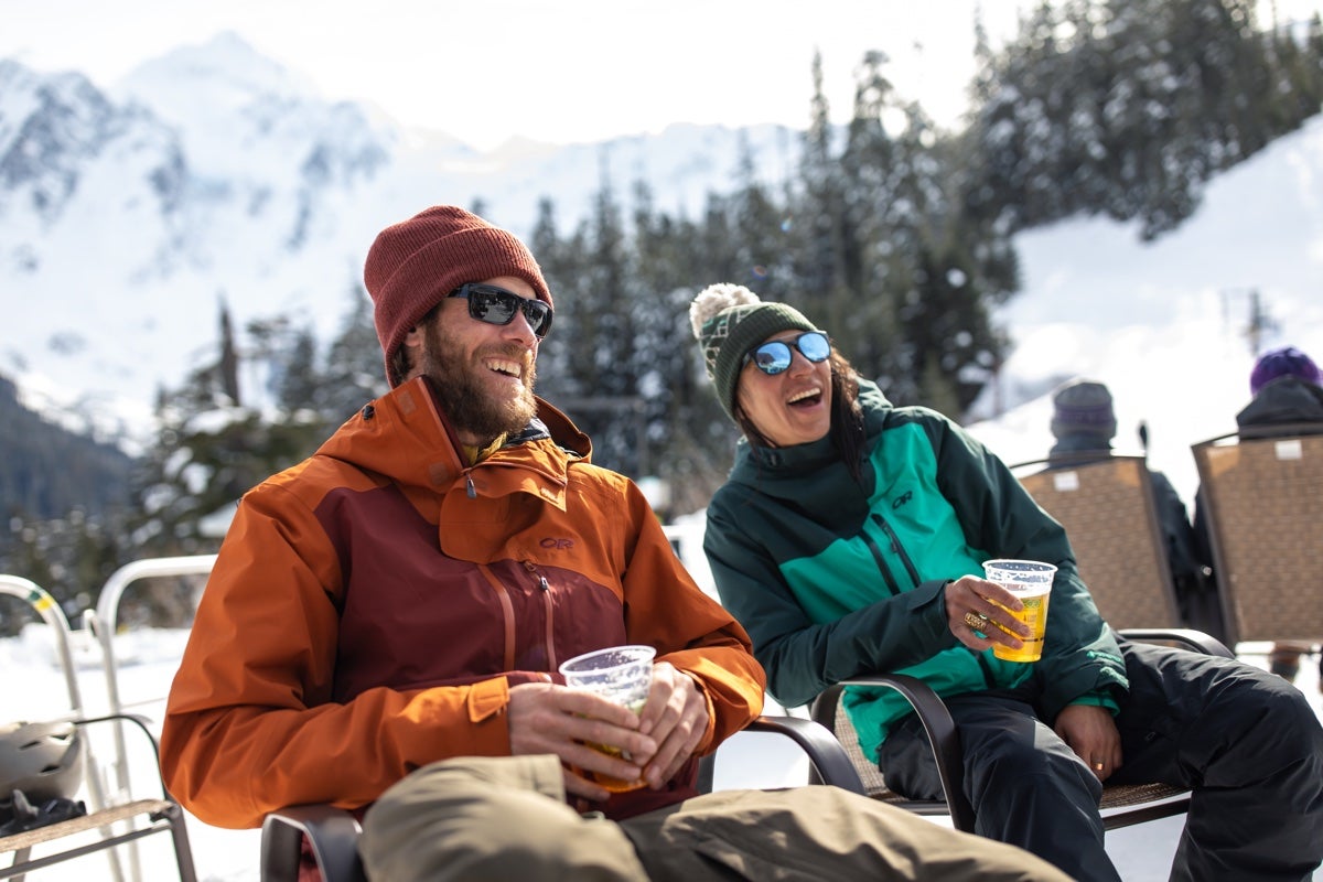 Two skiers enjoy a beverage after a day on the slopes.