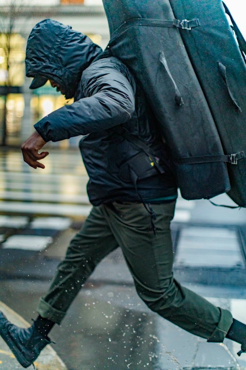 A traveler enjoys splashing in a puddle on a rainy city day.