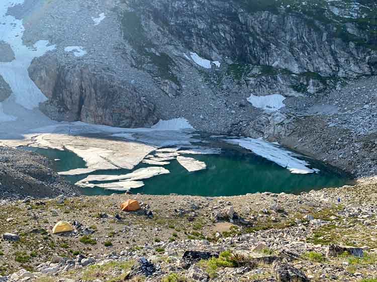 A family sets up camp near an alpine lake.