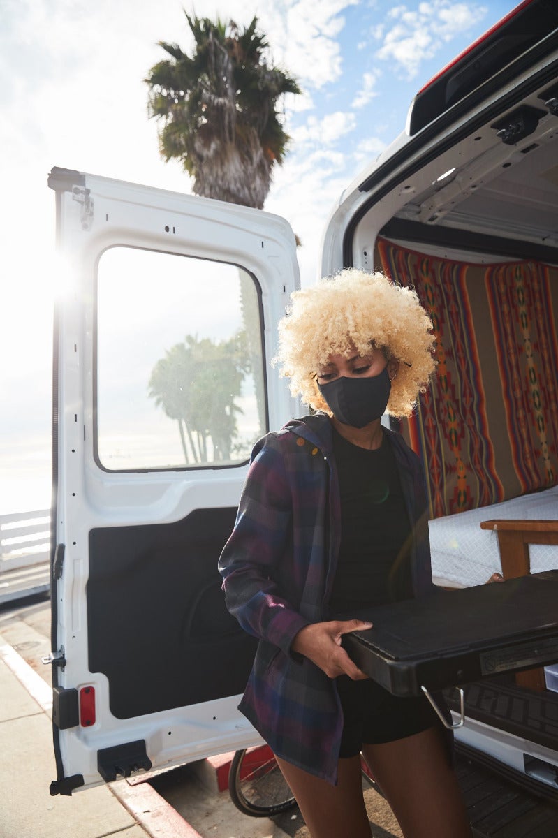 A woman wears the Outdoor Research face mask while unpacking her van.