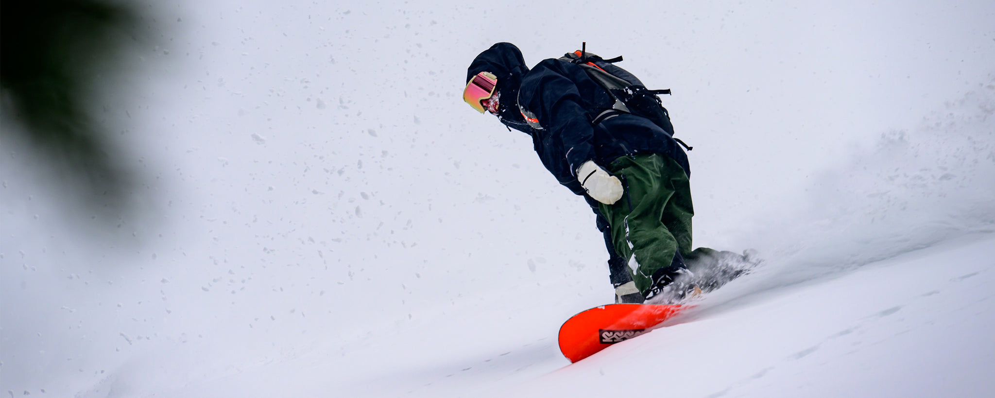 A man wears the Outdoor Research Hemispheres II Jacket while snowboarding.