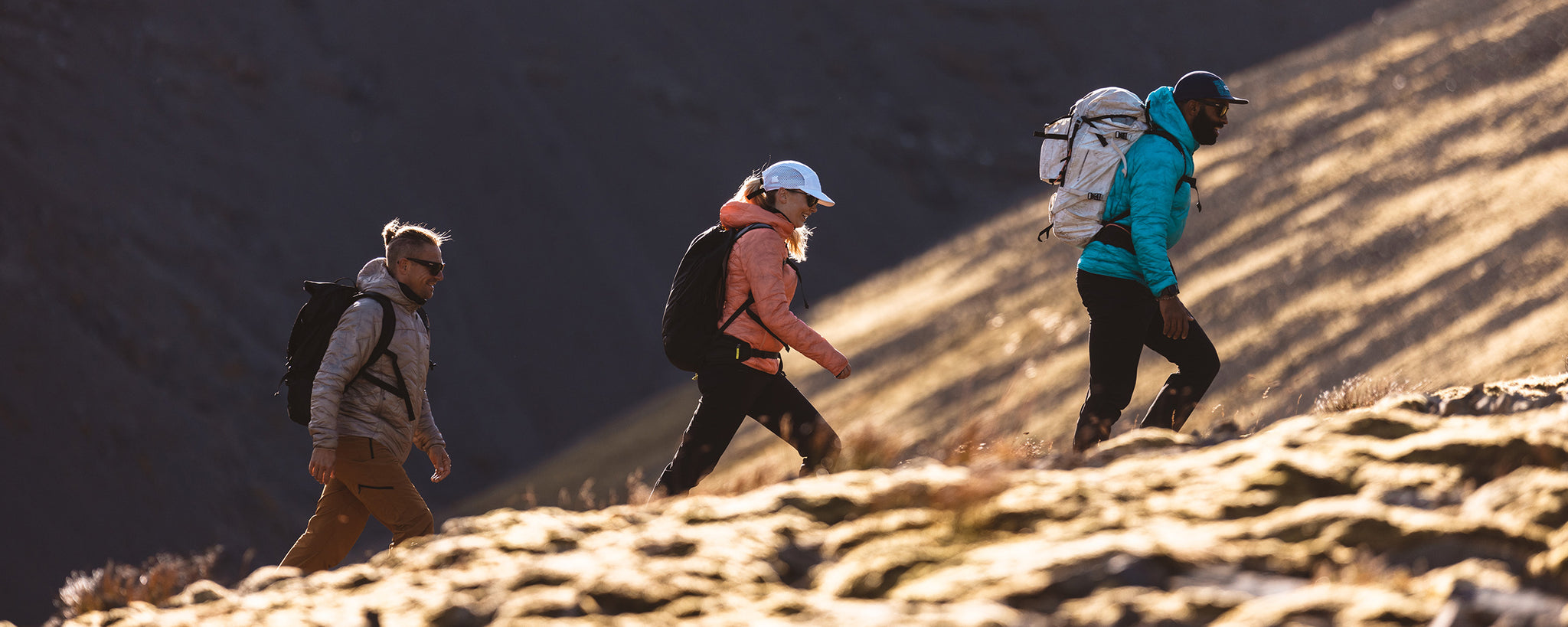 Three hikers ascend a rocky trail.