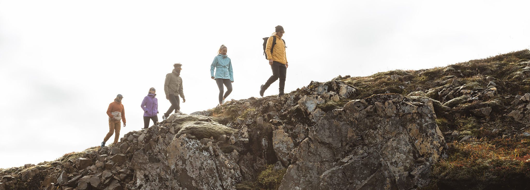 A group of friends hike along a rocky ridge.