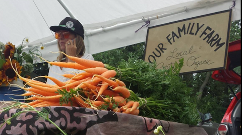 Our Family Farm sign behind market table with carrots on it