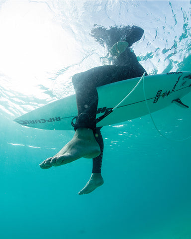 FCS Sharkbanz Pod being worn by a surfer connected to his leash in the water