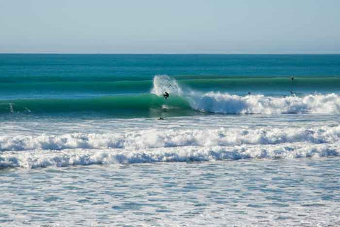 Surfers surfing at Wainui Beach in Gisborne, New Zealand
