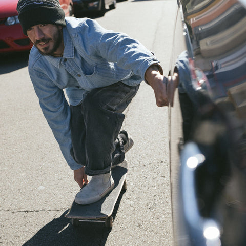 Skateboarder in grip stance being towed by a car