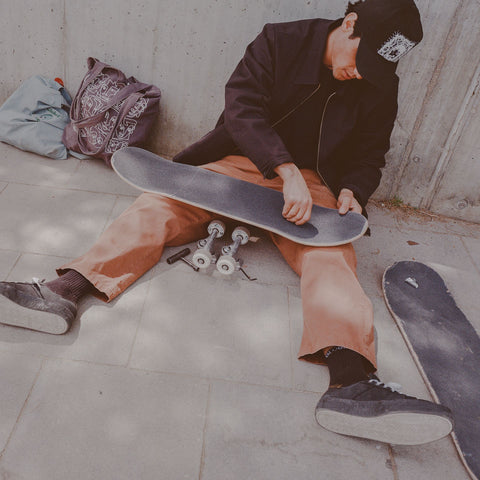 Globe sponsored skateboarder doing maintenance and repairs on his skateboard