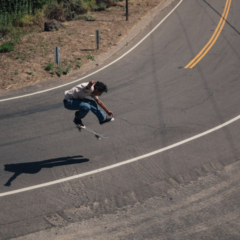 Skateboarder doing a massive ollie while skating downhill