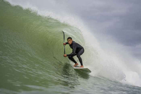 Image of local surfer Geoff Pardoe in a barrel in the Gisborne surf on his stand up paddleboard