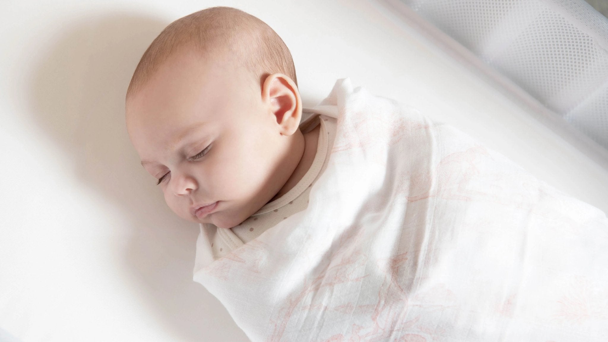 baby sleeps swaddled in muslin cloth