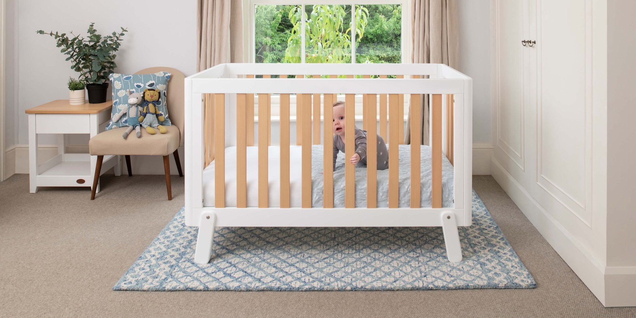 baby in two tone cot bed in light nursery