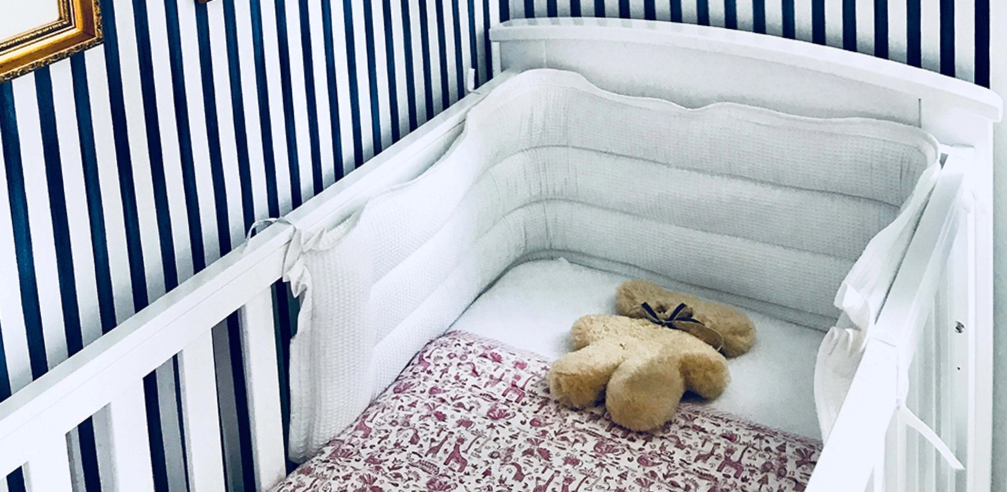 white cot bed with bumper and teddy