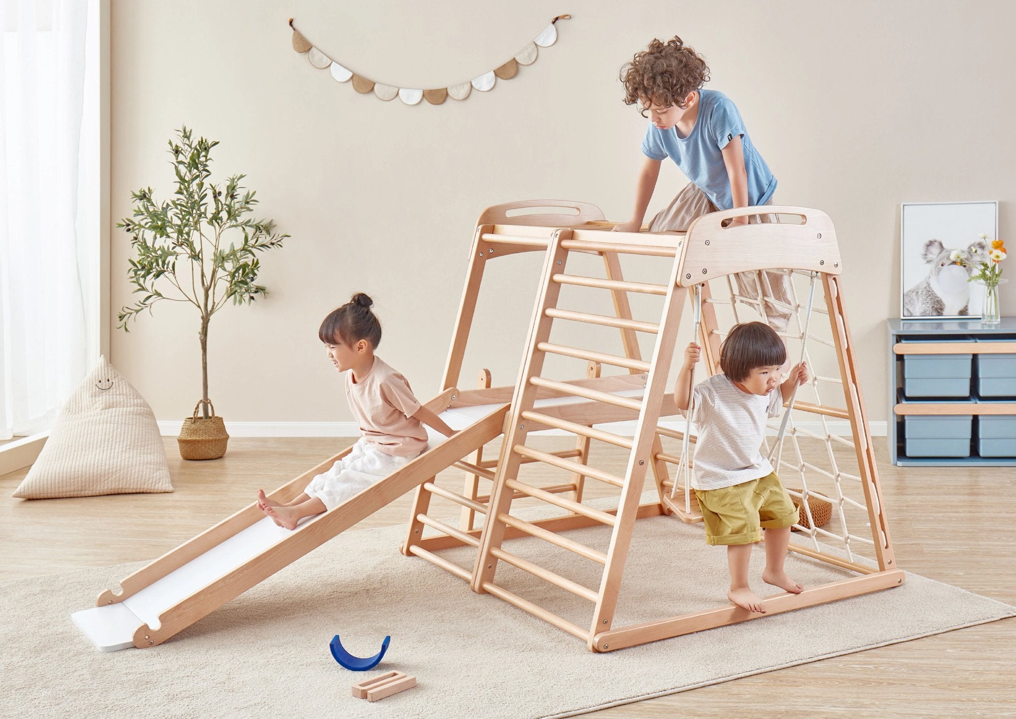 3 children play on indoor climbing gym in playroom