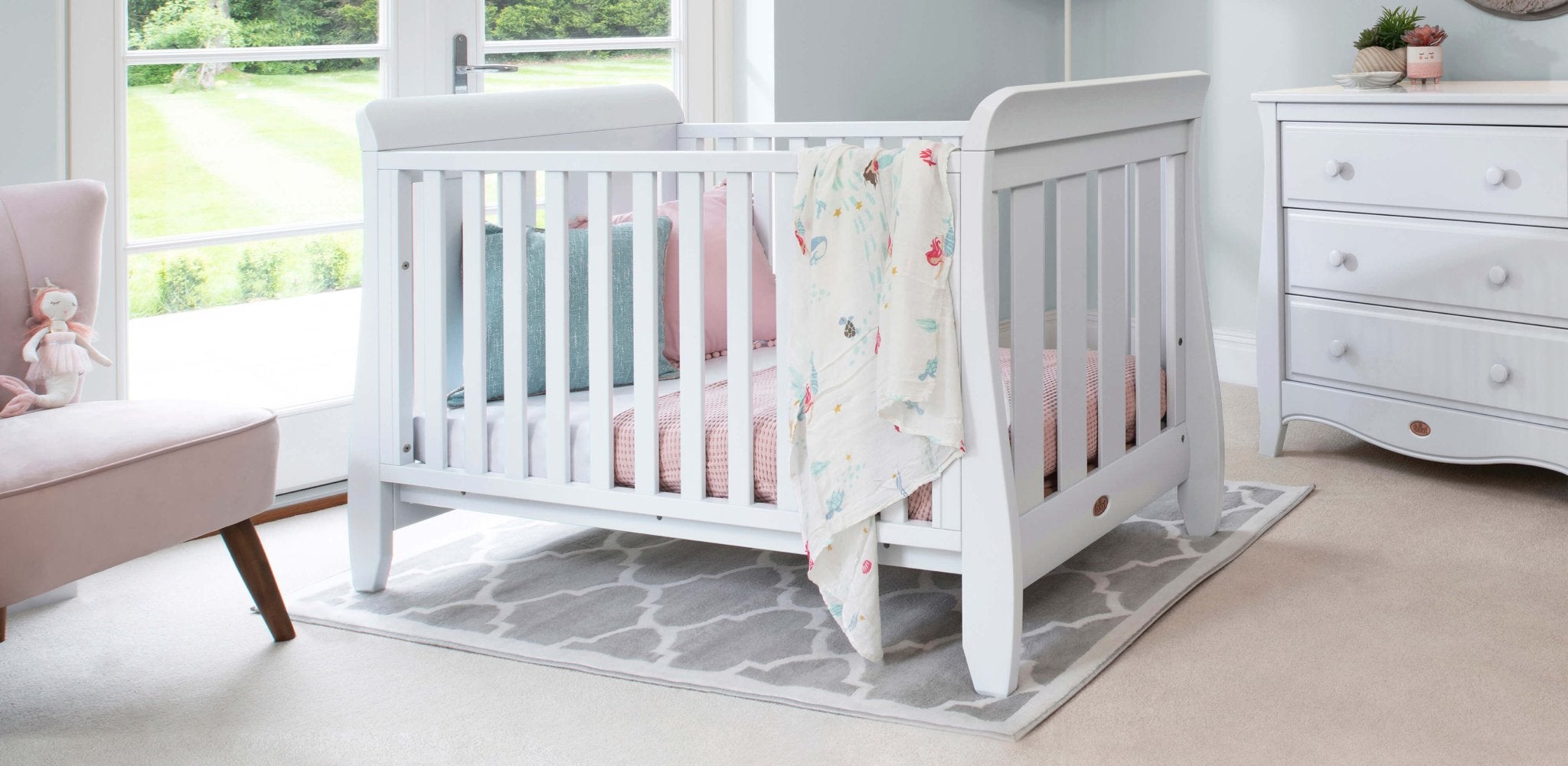 Sleigh cot bed in centre of bright nursery