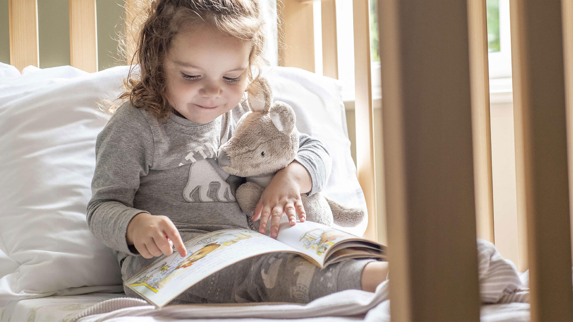 Girl reading with Kassie Kangaroo soft toy