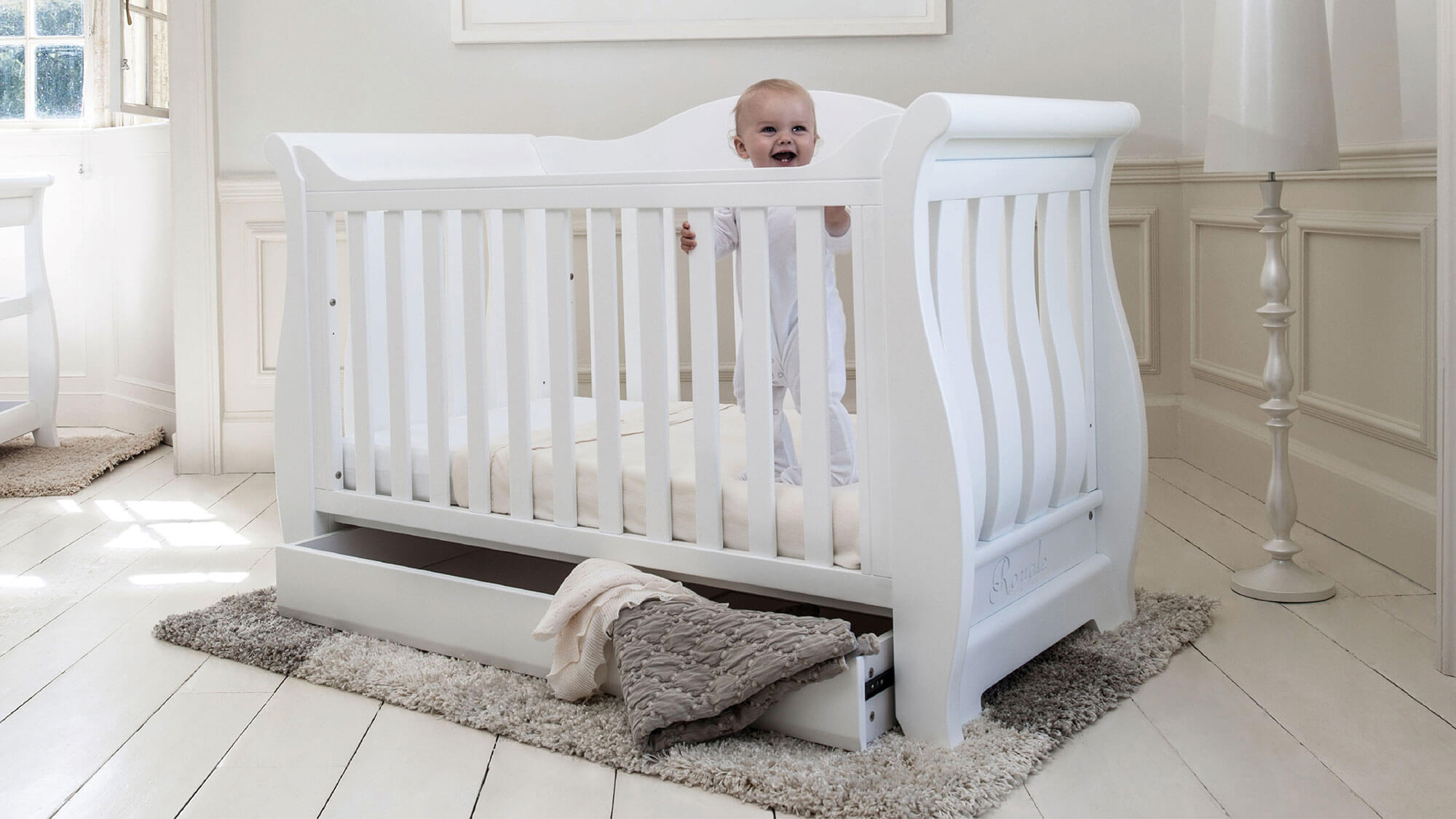 Baby in white Sleigh Royale Cot Bed