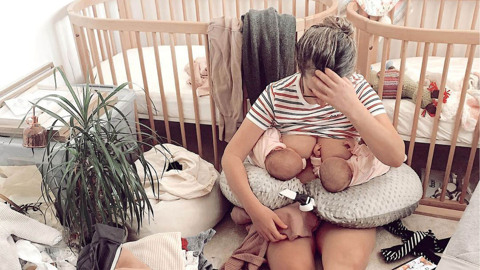 Mum looking upset breastfeeding twins