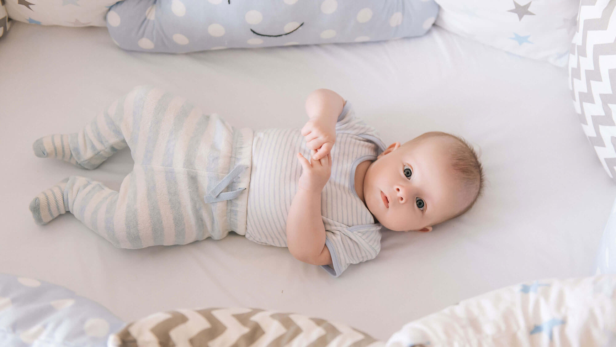 Baby in a cot with bumpers