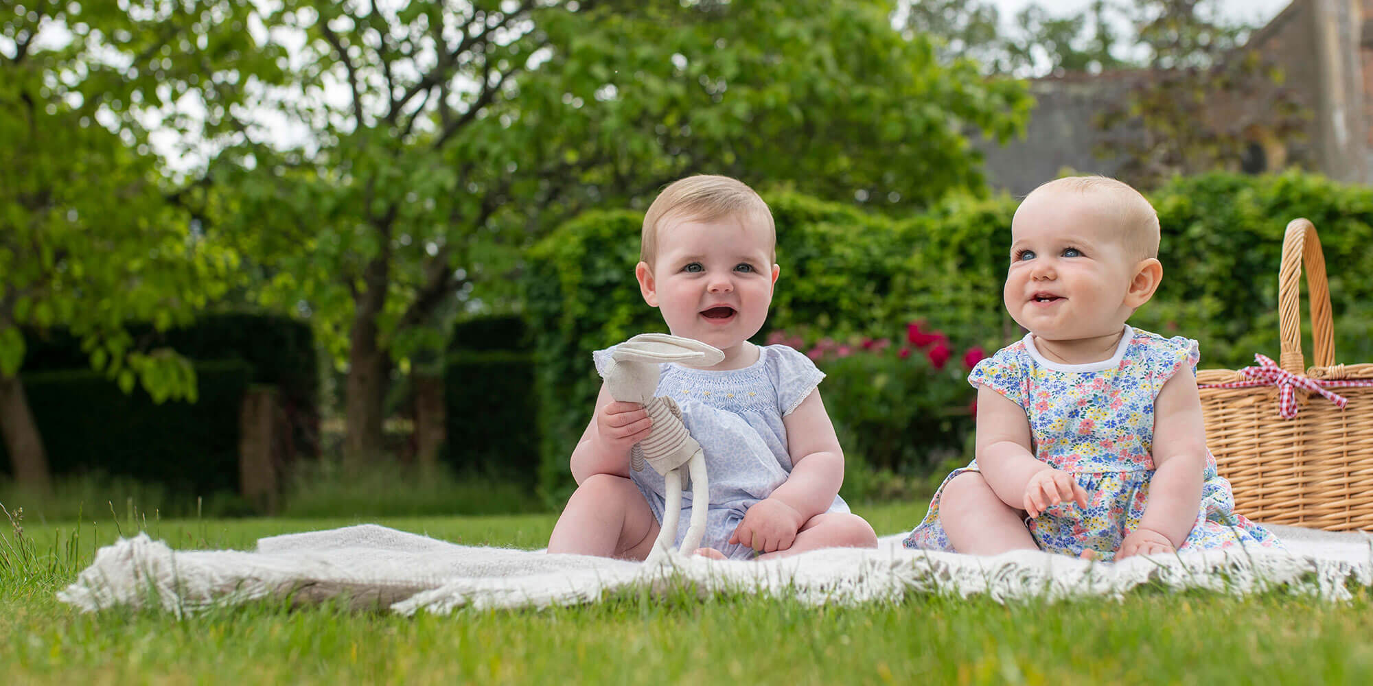 Twins sat on a picnic blanket in the garden