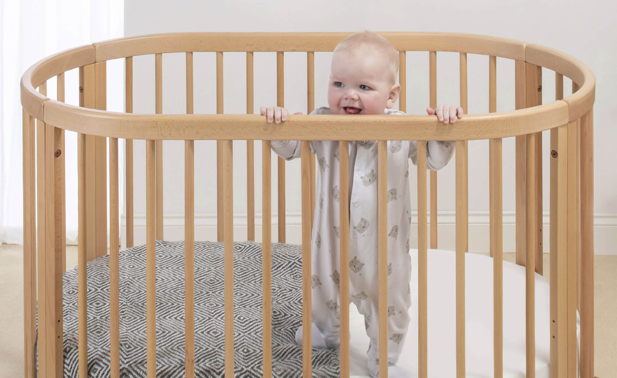 Baby standing in Oasis Oval Cot