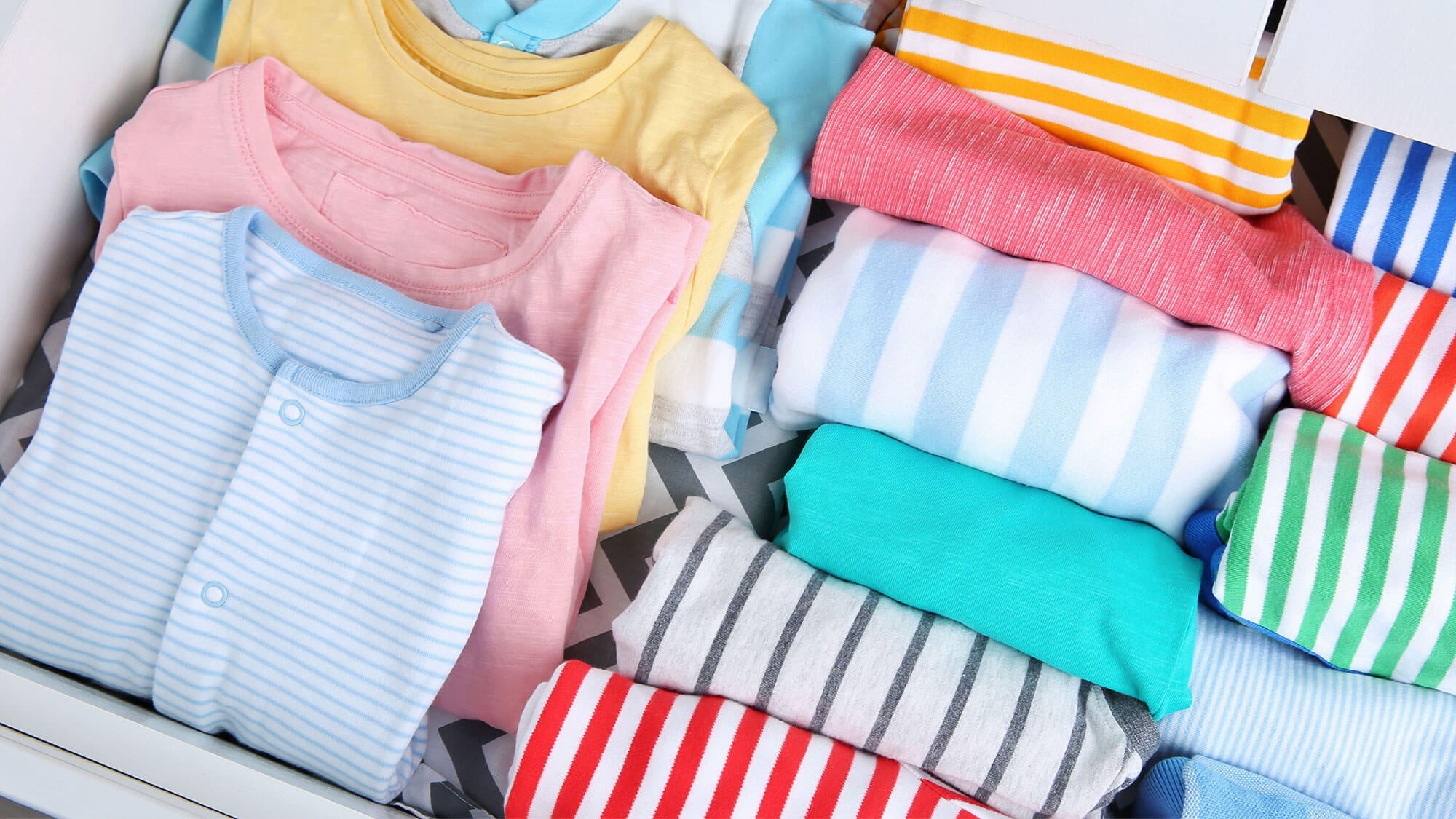 Baby clothes organised in a drawer
