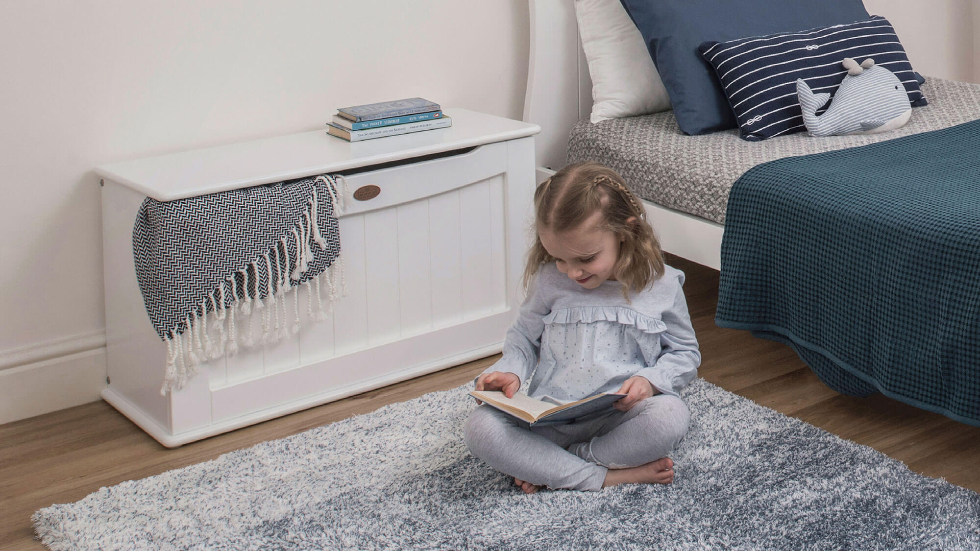 Girl sat reading next to Toy Box