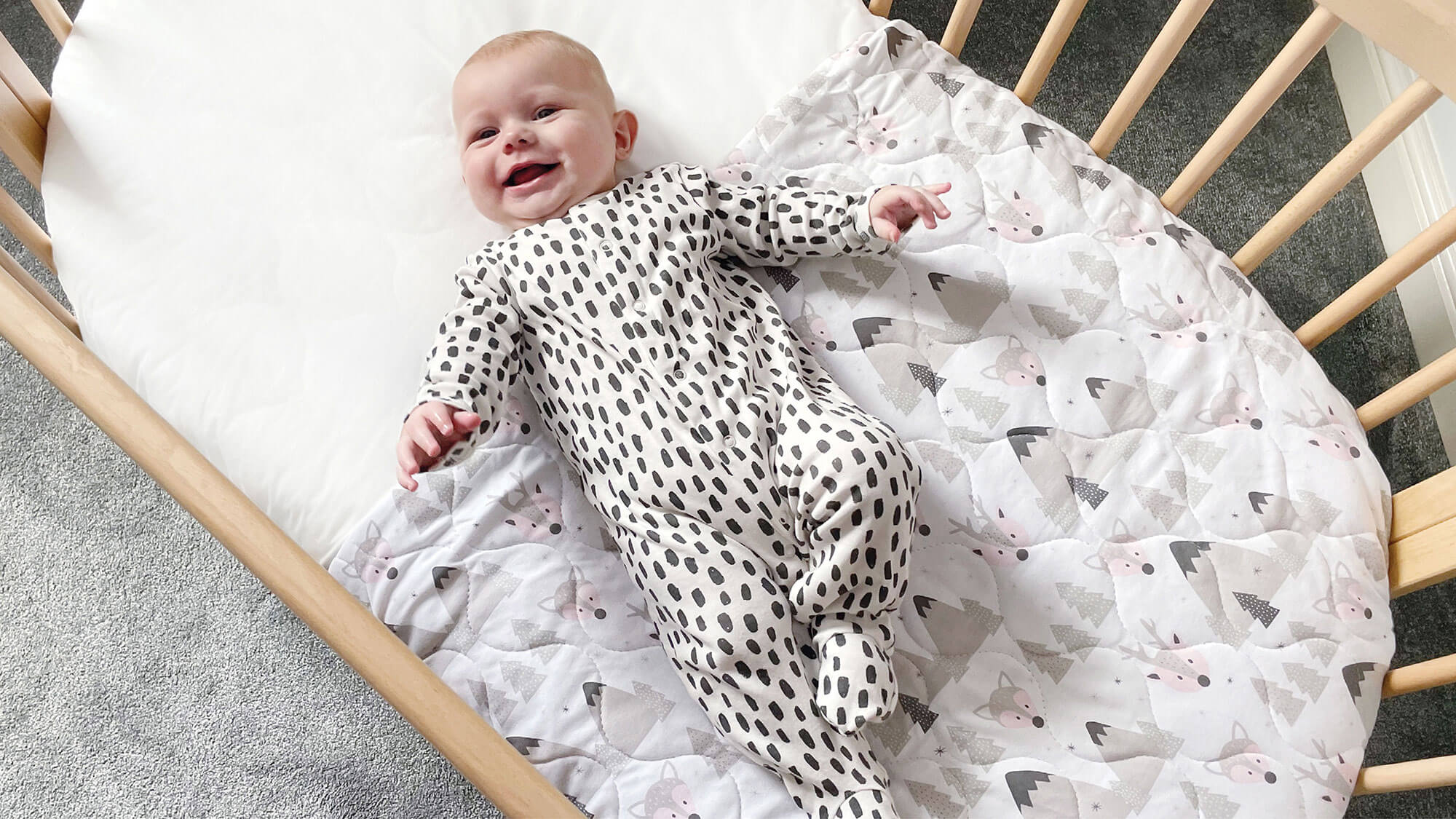 Baby on coverlet blanket in Oasis Oval Cot