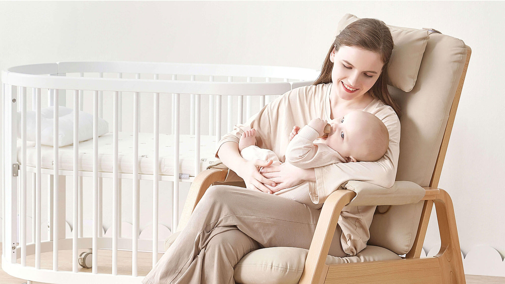 Mum sat on nursing chair with baby next to cot