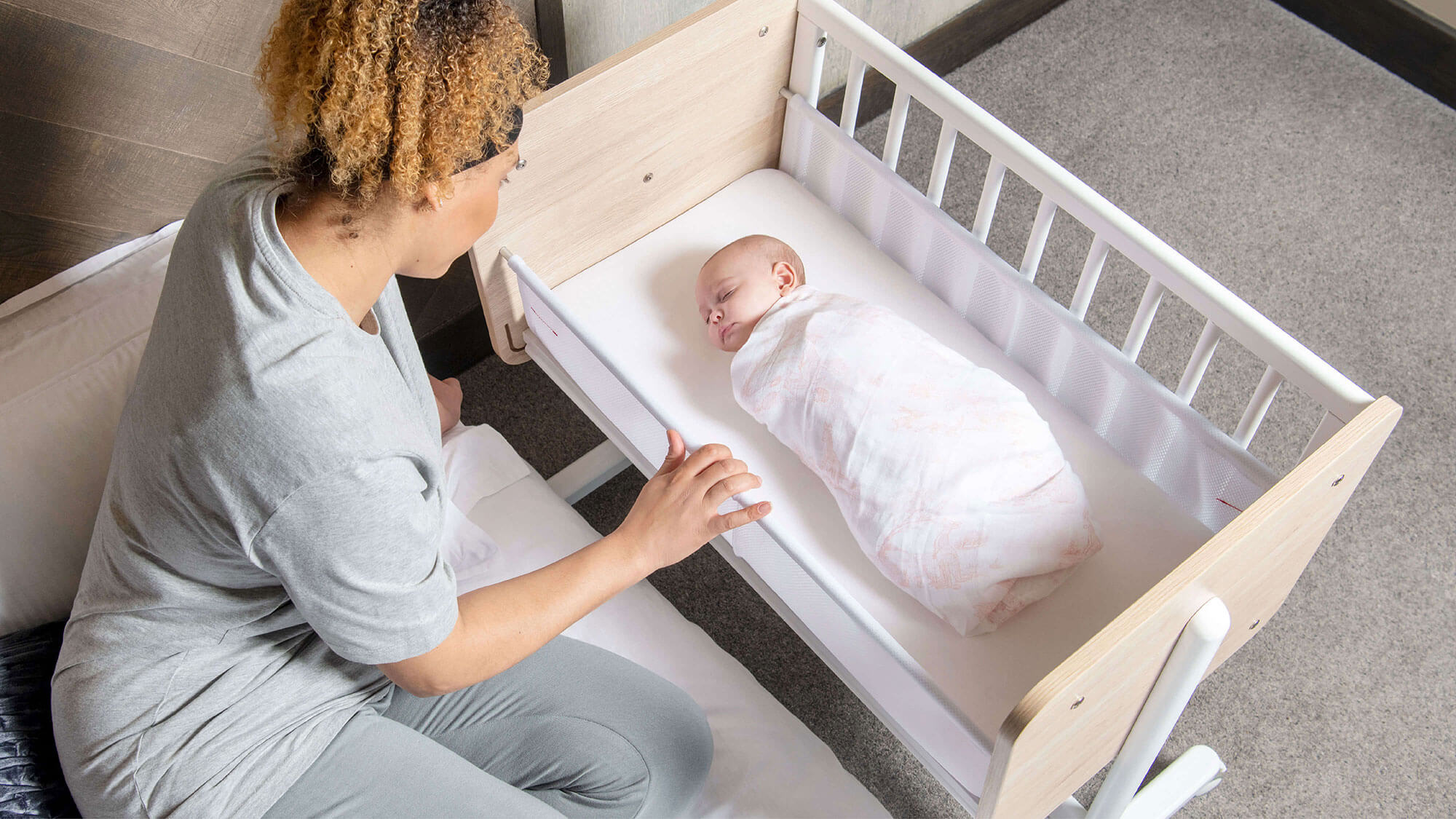 Mum in bed with baby in bedside crib