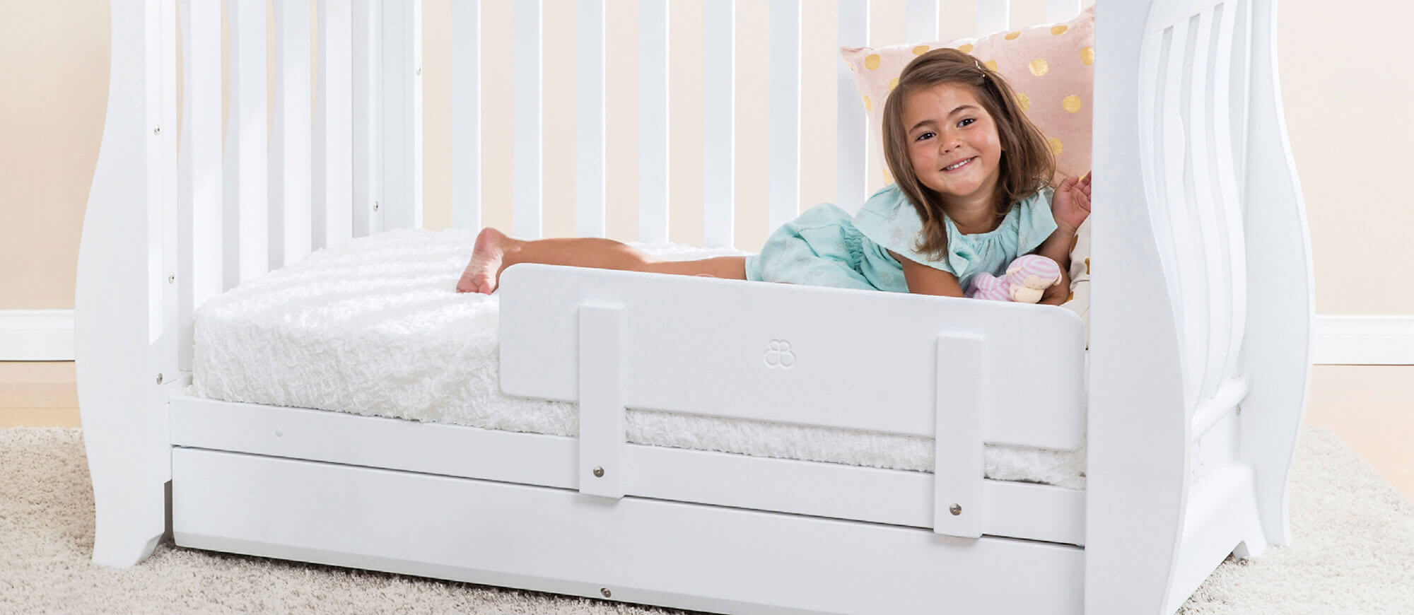 Little girl in cot bed with toddler guard panel