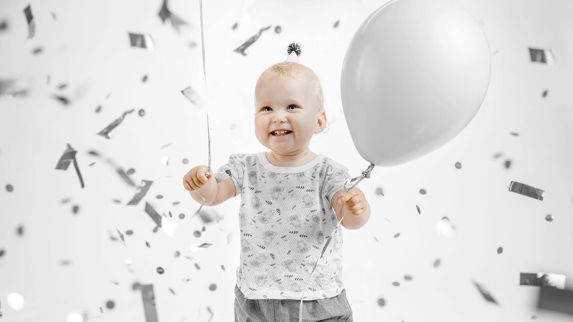 Baby with silver balloon and confetti