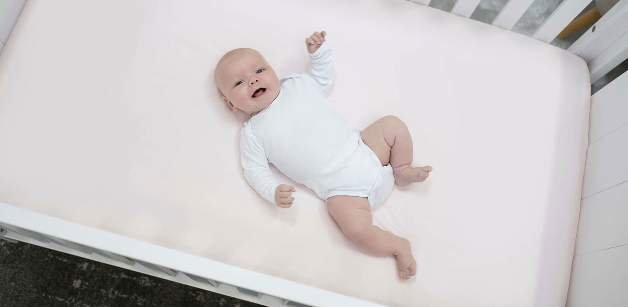 Baby on pink cot bed mattress