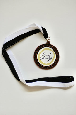 Image of an artwork that is a sports medal with the text "Good Enough" written in it.