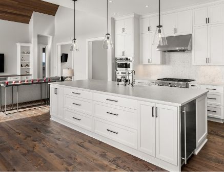 A modern kitchen that looks newly remodeled. The kitchen features white cabinets, whiter marble countertops, and vintage class bulb lighting.