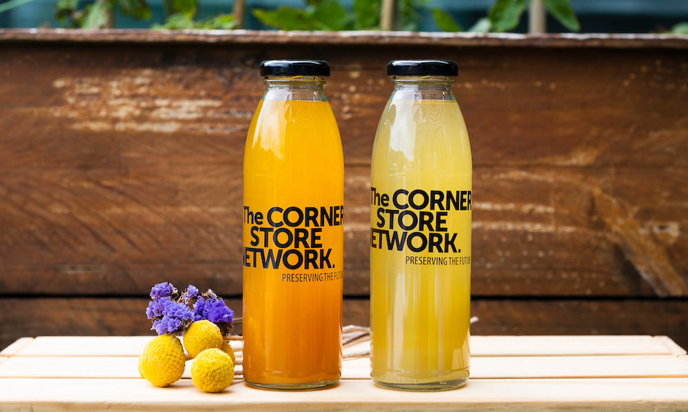 mandarin cordial and lemon cordial bottles stacked on timber planter box