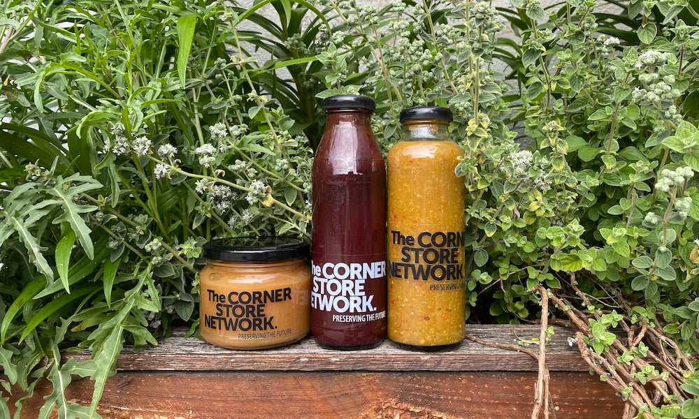 jars of hot sauce, plum sauce and apple sauce lined up on timber planter box