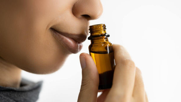a closeup of a woman smelling essential oils