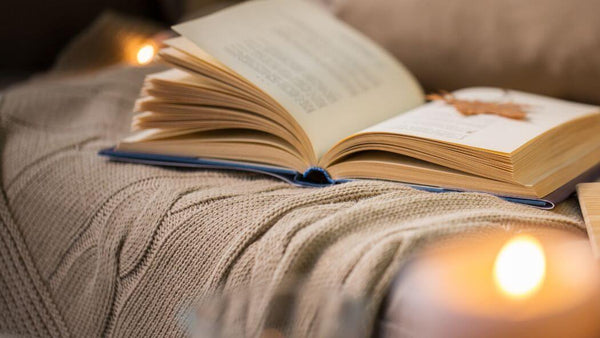 a book, a blanket and a lit candle