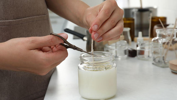 person cutting a cotton wick with scissors