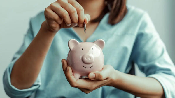 a woman putting a coin in a piggy bank