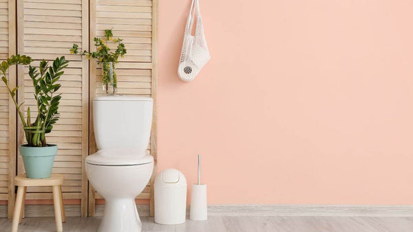 A toilet in a pink themed bathroom