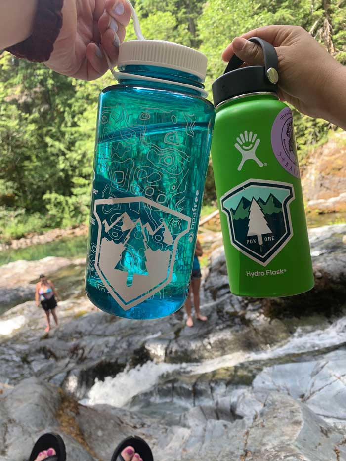 Outdoor photo of two water bottles featuring Next Adventure stickers