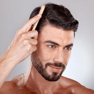 Up close image of a man combing a full set of hair, for our blog post on Nutrafol Products for Thinning Hair in Men